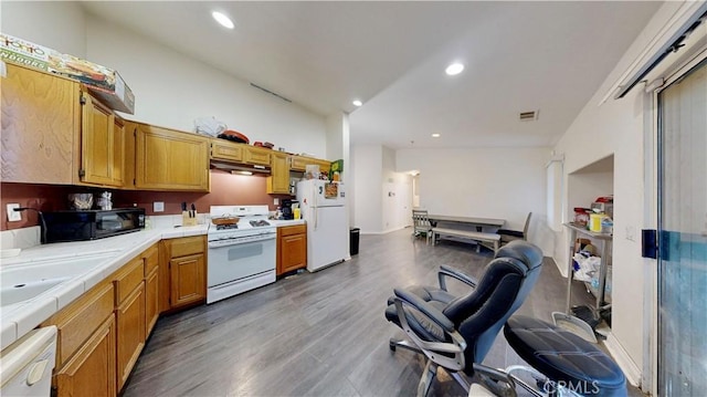 kitchen featuring recessed lighting, tile counters, white appliances, and wood finished floors