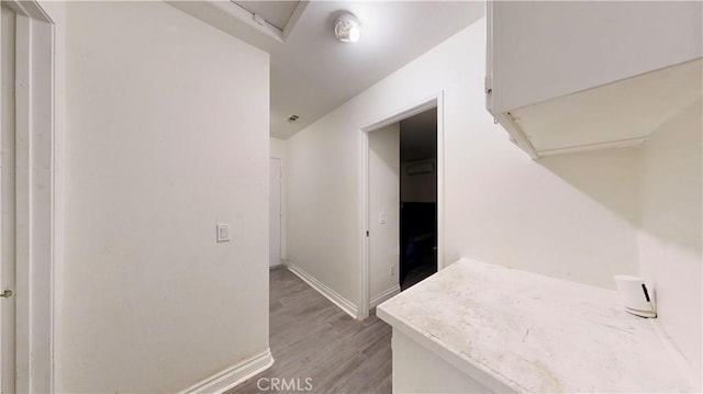 corridor featuring baseboards and light wood-style flooring