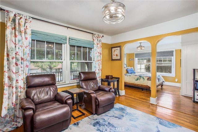 interior space featuring baseboards, arched walkways, and wood finished floors