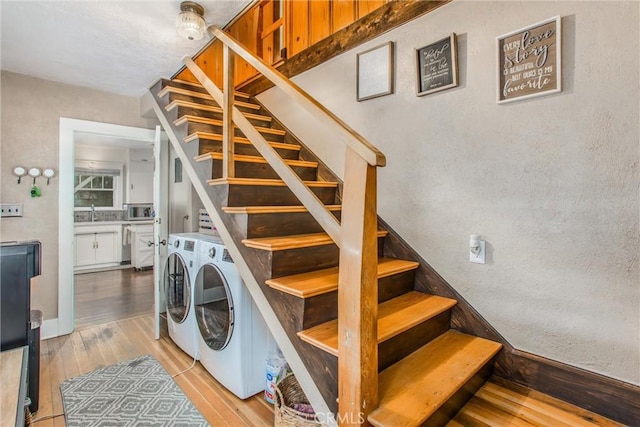 stairs with washing machine and clothes dryer, a textured wall, and wood-type flooring