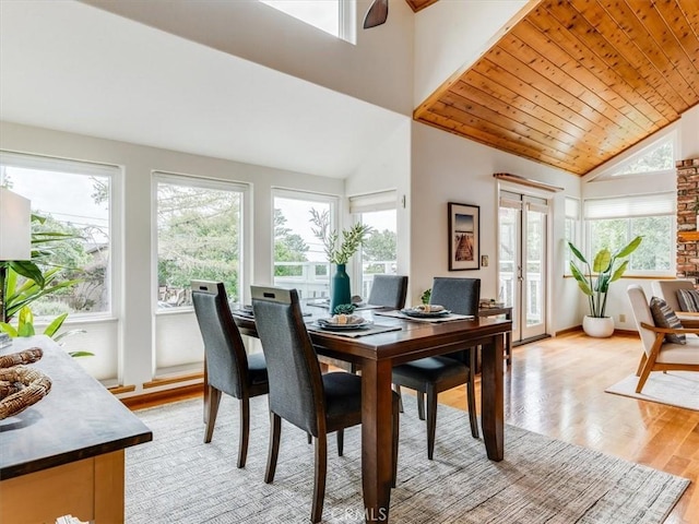 dining area with high vaulted ceiling and light wood-style flooring