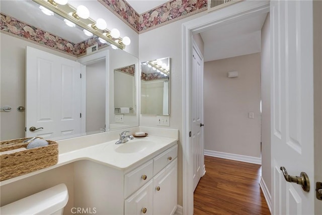 bathroom featuring wood finished floors, visible vents, toilet, vanity, and baseboards