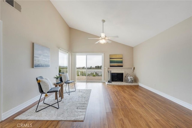 sitting room featuring baseboards, visible vents, a ceiling fan, wood finished floors, and a fireplace