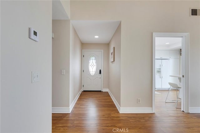 foyer entrance with baseboards, wood finished floors, and visible vents
