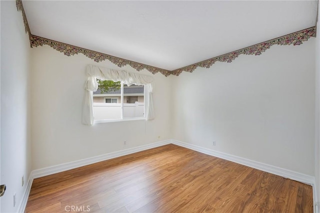 empty room featuring baseboards and light wood finished floors