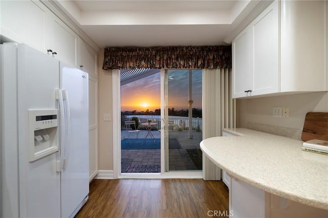 kitchen featuring white cabinets, dark wood-type flooring, white refrigerator with ice dispenser, and light countertops