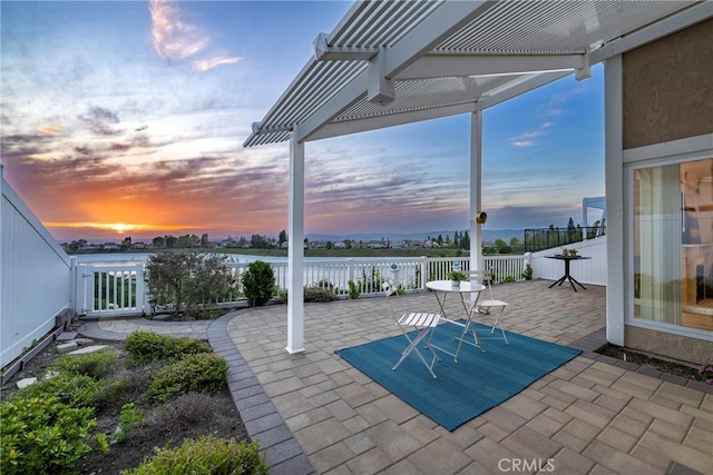 patio terrace at dusk with a pergola and a water view