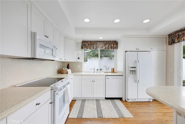 kitchen featuring white cabinets, plenty of natural light, white appliances, and a sink