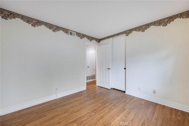 unfurnished room with baseboards, light wood-style floors, and visible vents