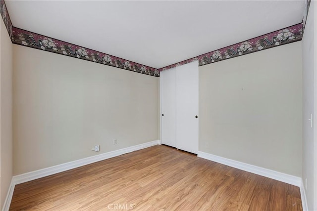 spare room featuring baseboards and light wood finished floors