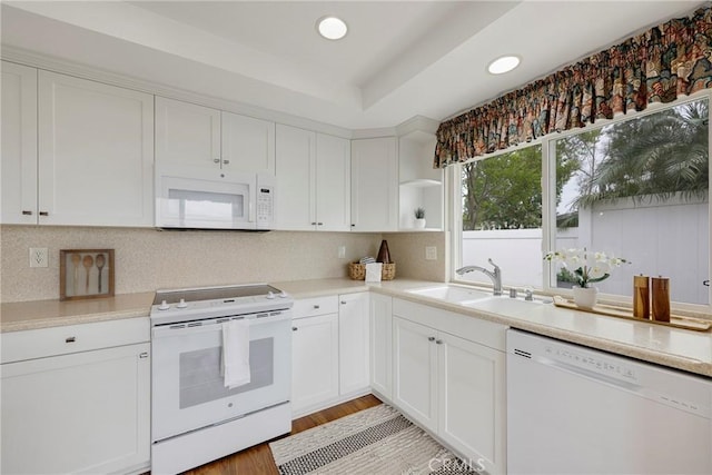 kitchen featuring white cabinets, a sink, white appliances, and light countertops