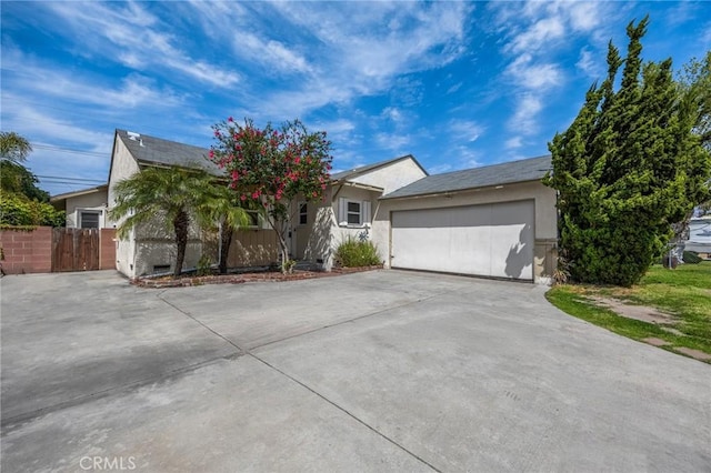 ranch-style house with stucco siding, an attached garage, driveway, and fence