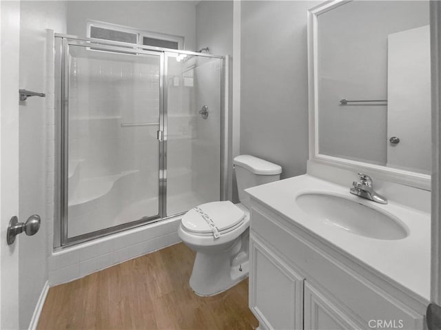 full bathroom featuring toilet, vanity, a shower stall, and wood finished floors