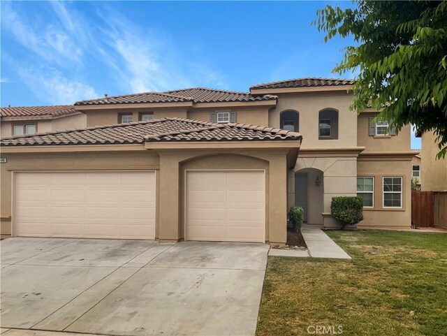 mediterranean / spanish-style home with concrete driveway, a tiled roof, stucco siding, a front lawn, and a garage