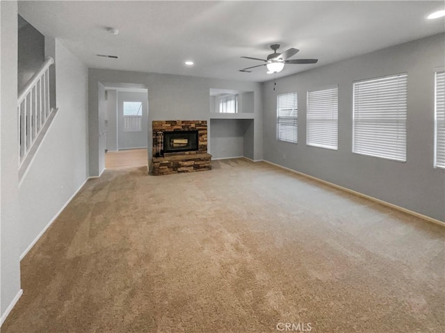 unfurnished living room with carpet floors, a wealth of natural light, a ceiling fan, and baseboards