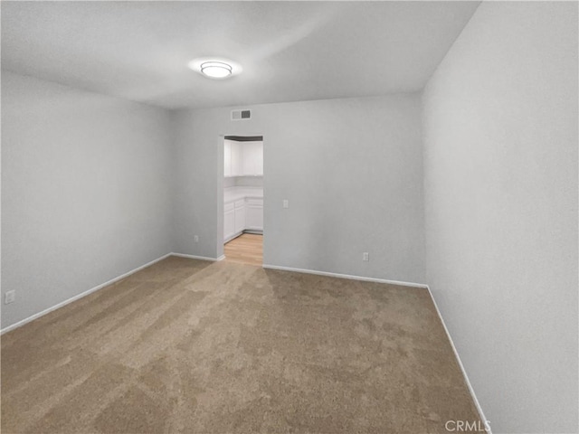 empty room with baseboards, visible vents, and light colored carpet