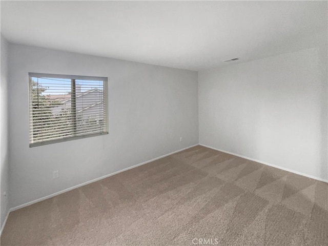 unfurnished room featuring baseboards, visible vents, and carpet flooring
