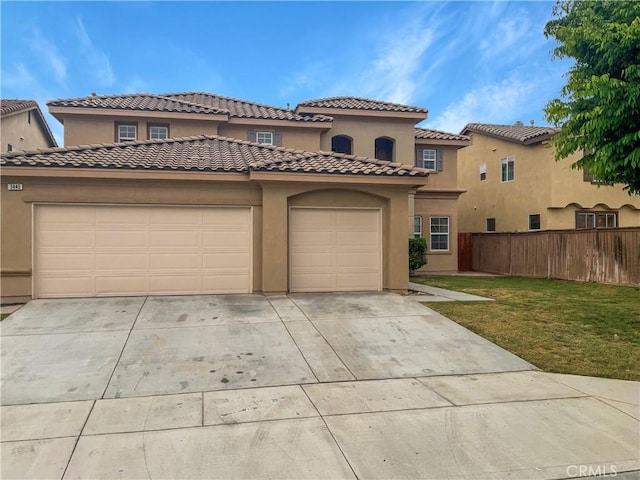 mediterranean / spanish home featuring a front yard, an attached garage, concrete driveway, stucco siding, and fence