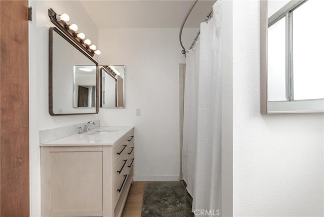 bathroom featuring a shower with shower curtain, baseboards, wood finished floors, and vanity