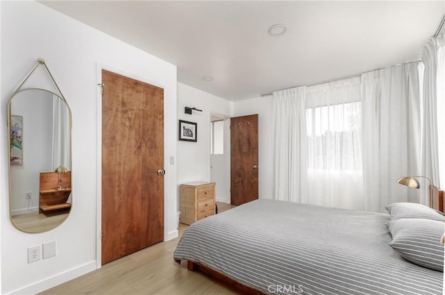bedroom with baseboards and light wood finished floors