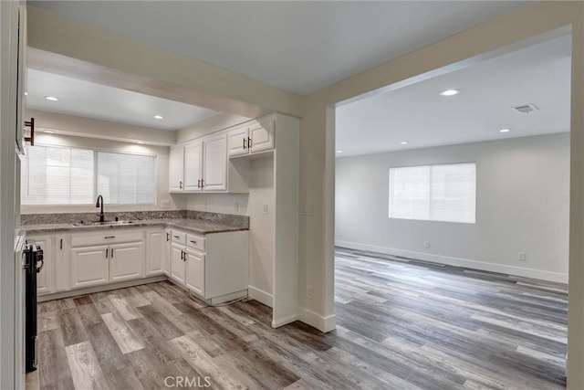 402 E Glendale Dr, Orange, CA 92865 - kitchen with a sink, light wood-style flooring, white cabinets, light stone counters, and recessed lighting