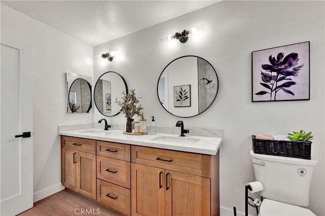 full bath featuring double vanity, toilet, wood finished floors, and a sink