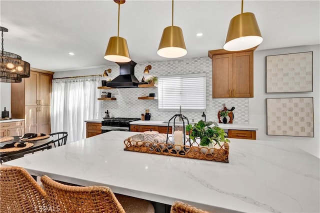 kitchen with premium range hood, backsplash, stainless steel range with gas stovetop, and a wealth of natural light