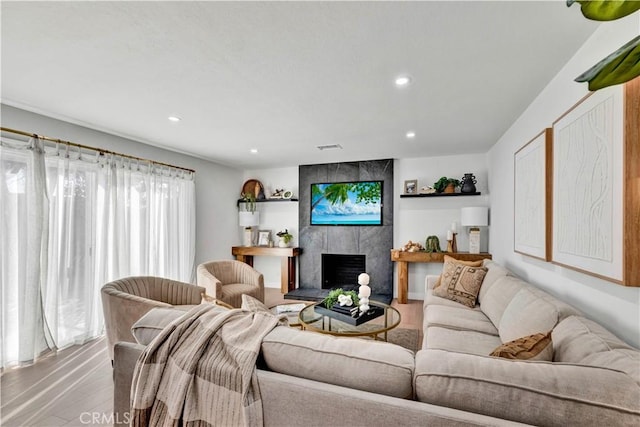 living room with a fireplace, visible vents, light wood finished floors, and recessed lighting
