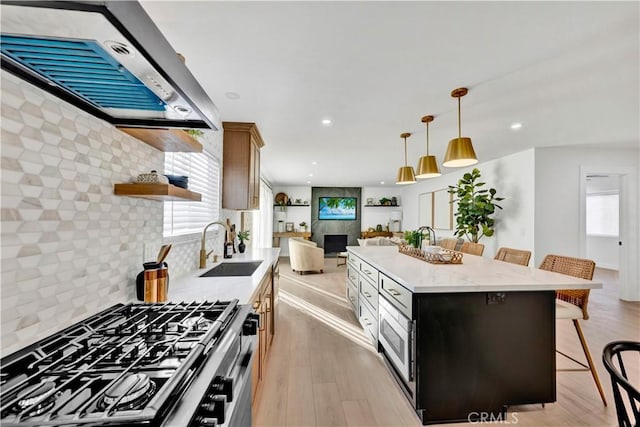 kitchen featuring exhaust hood, open shelves, a sink, stainless steel range with gas cooktop, and a kitchen bar