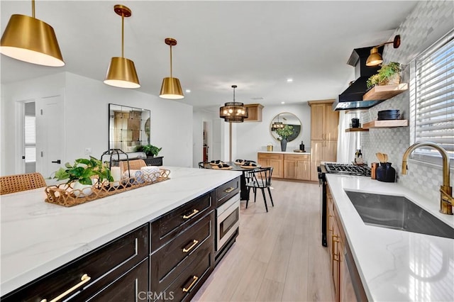 kitchen featuring range with gas cooktop, open shelves, a sink, light wood-type flooring, and wall chimney exhaust hood
