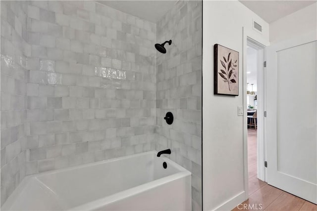 bathroom with baseboards, visible vents, wood finished floors, and  shower combination