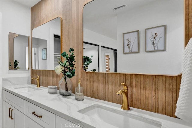 bathroom with double vanity, visible vents, and a sink