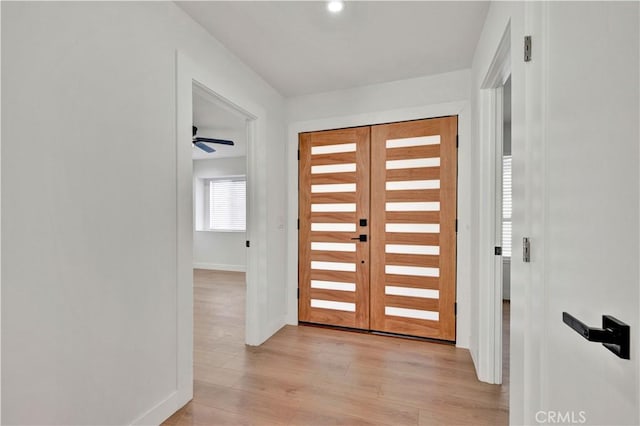 entryway with ceiling fan, baseboards, and light wood finished floors