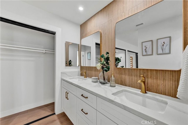 full bathroom with wood finished floors, a sink, visible vents, and double vanity
