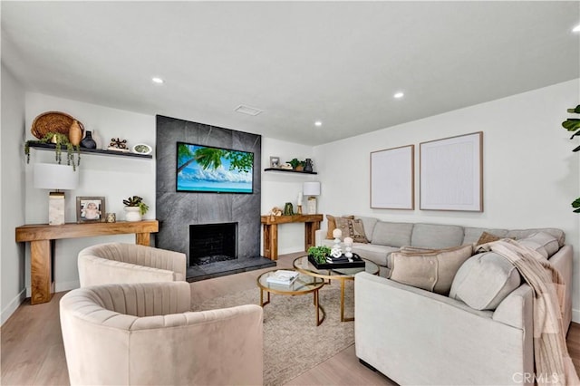 living room with recessed lighting, visible vents, baseboards, a fireplace, and light wood-style flooring