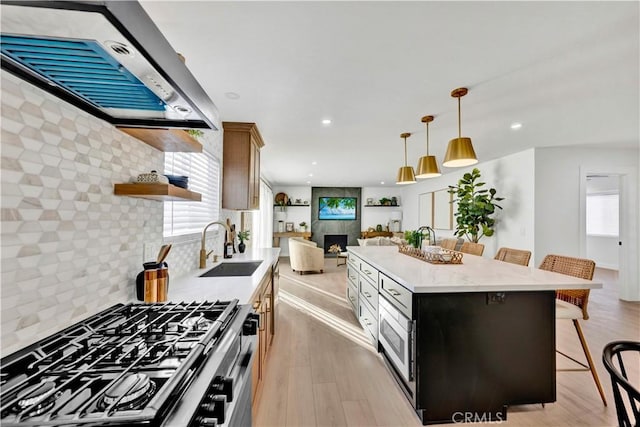 kitchen featuring open shelves, a sink, a breakfast bar, exhaust hood, and gas stove