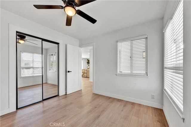 unfurnished bedroom with light wood-style floors, a closet, a ceiling fan, and baseboards