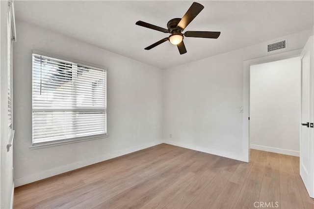 spare room with ceiling fan, baseboards, light wood-style floors, and visible vents