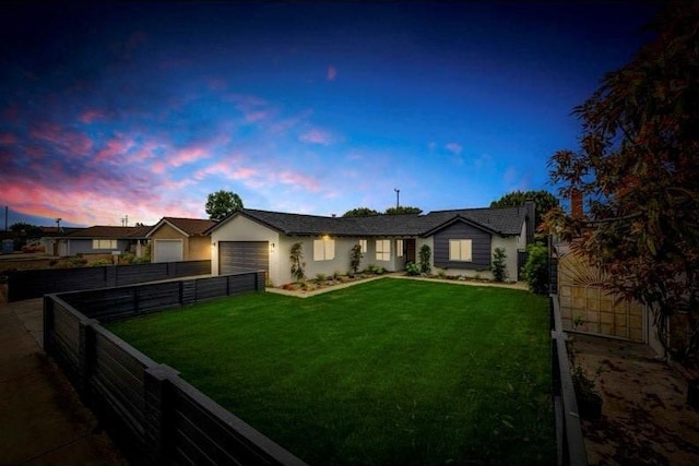 ranch-style house featuring stucco siding, a front lawn, fence private yard, and a garage