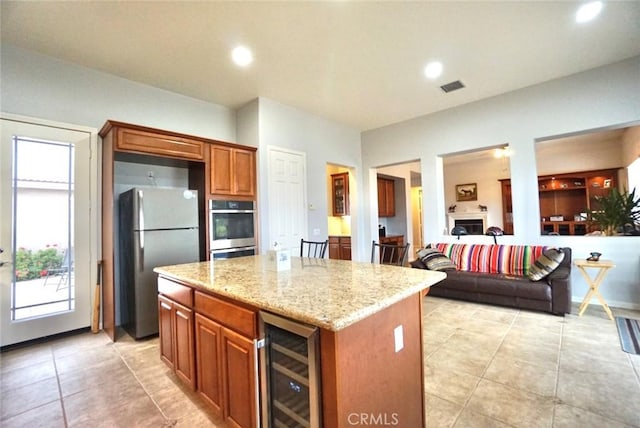 23801 Hollingsworth Dr, Murrieta, CA 92562 - kitchen featuring appliances with stainless steel finishes, light stone counters, beverage cooler, a center island, and visible vents