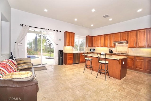 23801 Hollingsworth Dr, Murrieta, CA 92562 - kitchen with a breakfast bar area, backsplash, a center island, brown cabinets, and stainless steel appliances