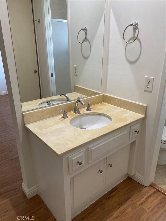 bathroom with baseboards, wood finished floors, toilet, and vanity