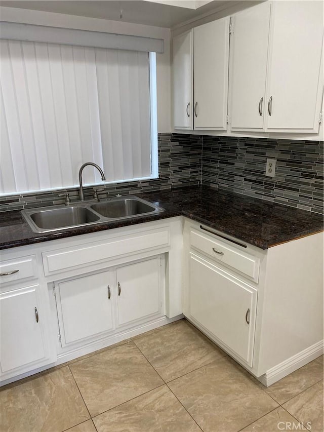 kitchen with white cabinets, decorative backsplash, and a sink