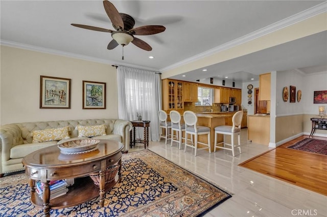living area featuring a ceiling fan, baseboards, crown molding, and recessed lighting