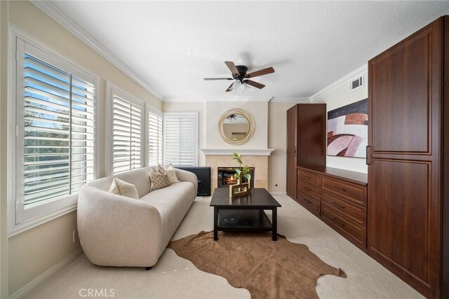 living area featuring ornamental molding, visible vents, ceiling fan, and light carpet