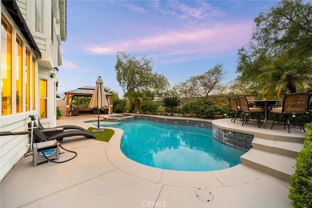15 Pebble Bch, Coto De Caza, CA 92679 - pool at dusk with a gazebo, a patio area, a pool with connected hot tub, a fenced backyard, and outdoor dining space