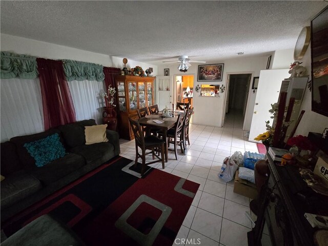 living area with a ceiling fan, light tile patterned flooring, and a textured ceiling