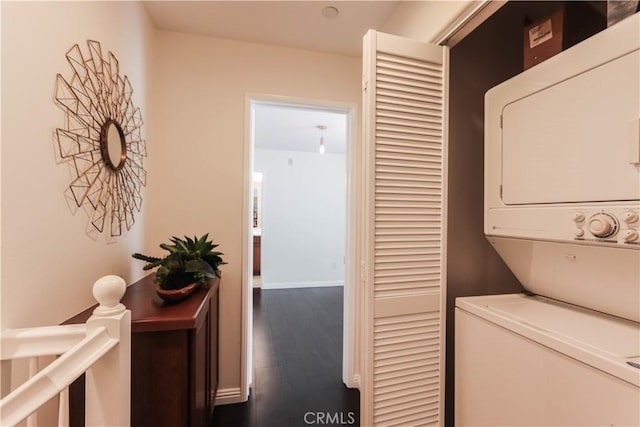 laundry area featuring baseboards, dark wood-style floors, stacked washer / dryer, and laundry area