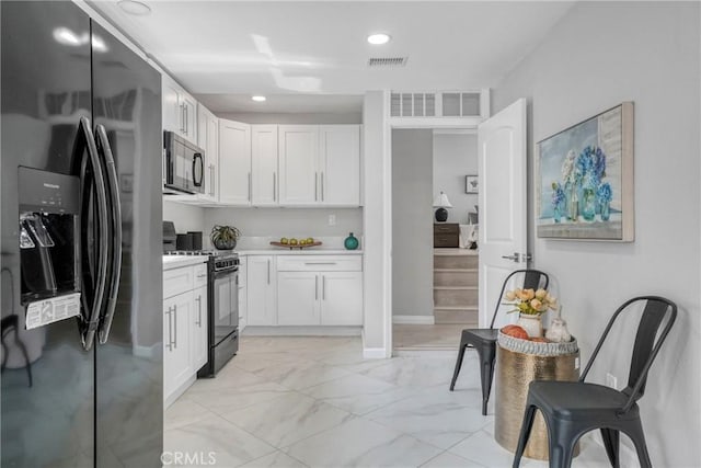 kitchen featuring baseboards, white cabinetry, marble finish floor, light countertops, and black appliances