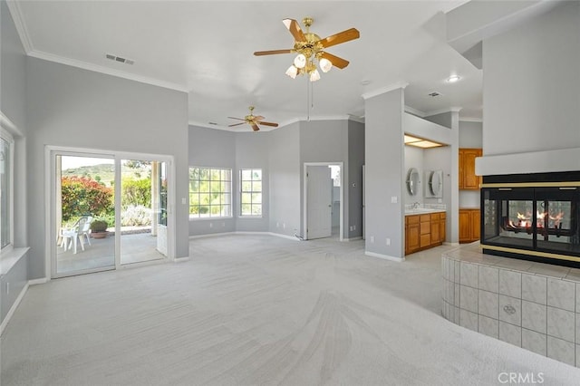 unfurnished living room featuring a ceiling fan, crown molding, light colored carpet, baseboards, and visible vents